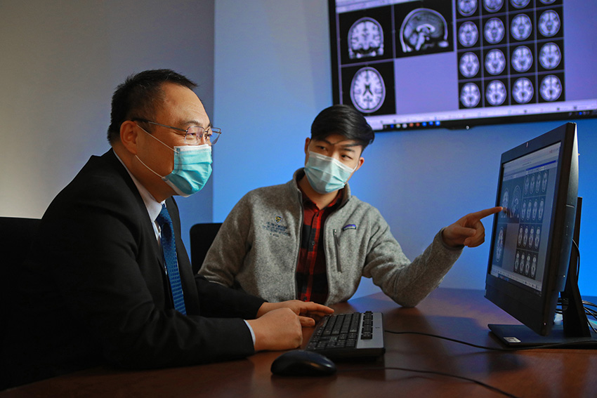 Xin Wang, M.D., Ph.D., and David Liu looking at MRI images on a computer